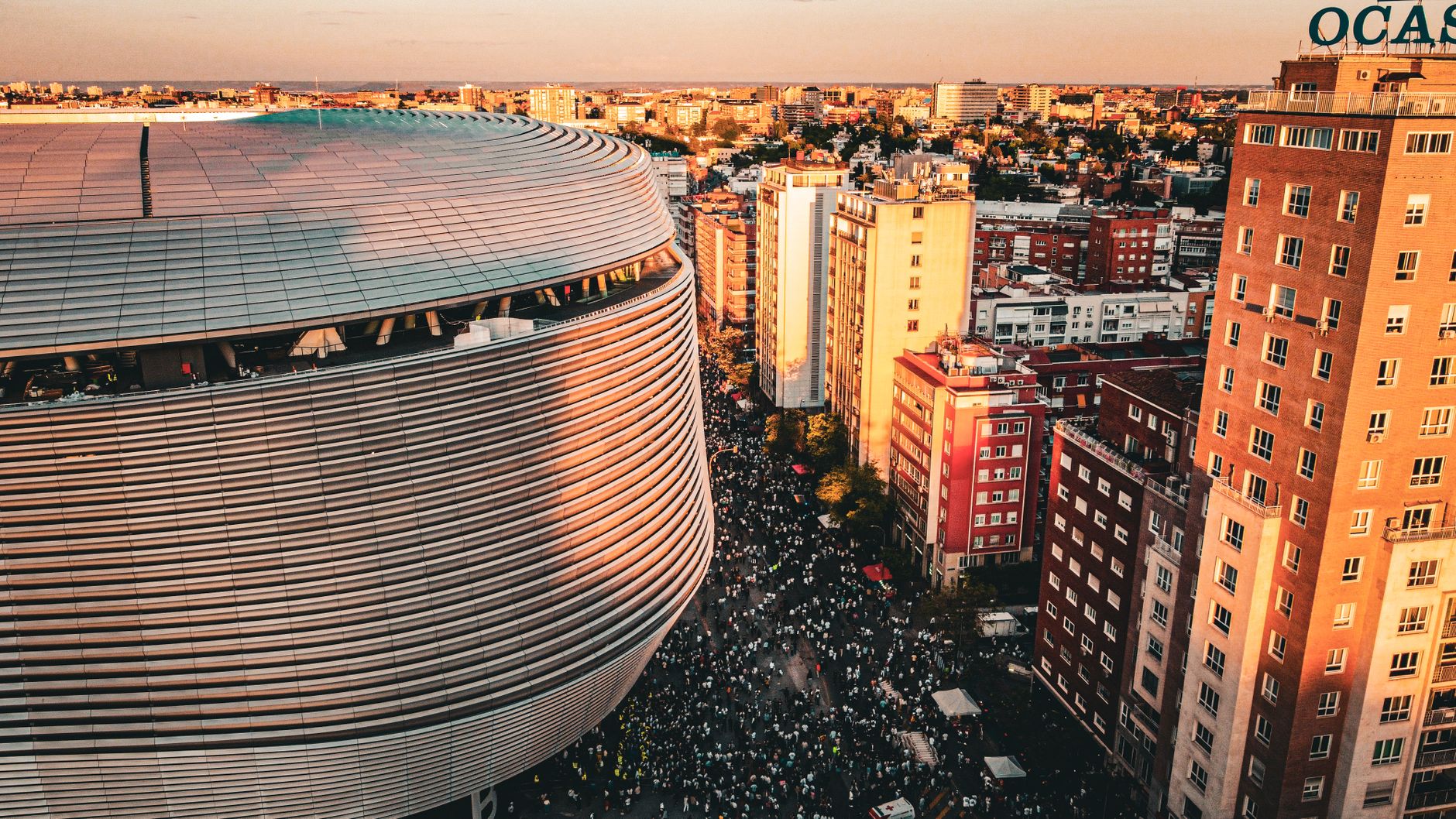 Aerial view of a stadium and bustling cityscape in Madrid, Spain during sunset.