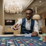 A man in formal attire plays roulette in a luxurious casino under a chandelier.