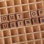 Wooden blocks spelling 'Out of Business', conveying closure or financial difficulties.