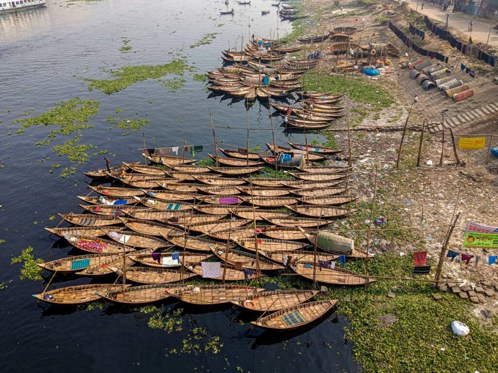 Aerial view of traditional wooden boats docked along a riverbank in Bangladesh.