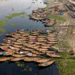 Aerial view of traditional wooden boats docked along a riverbank in Bangladesh.