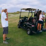 Group of people enjoying a day at the golf course with a golf cart.