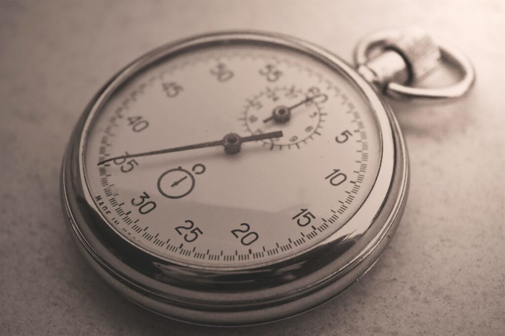An antique silver pocket watch captured in a sepia tone, showcasing intricate details.