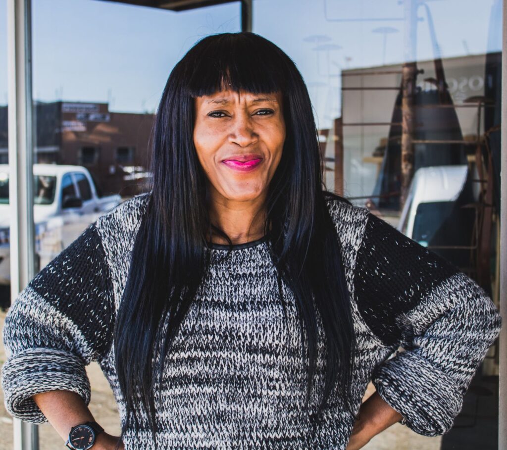 Portrait of a smiling woman wearing a knitted sweater outdoors, capturing her vibrant personality.