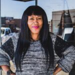 Portrait of a smiling woman wearing a knitted sweater outdoors, capturing her vibrant personality.