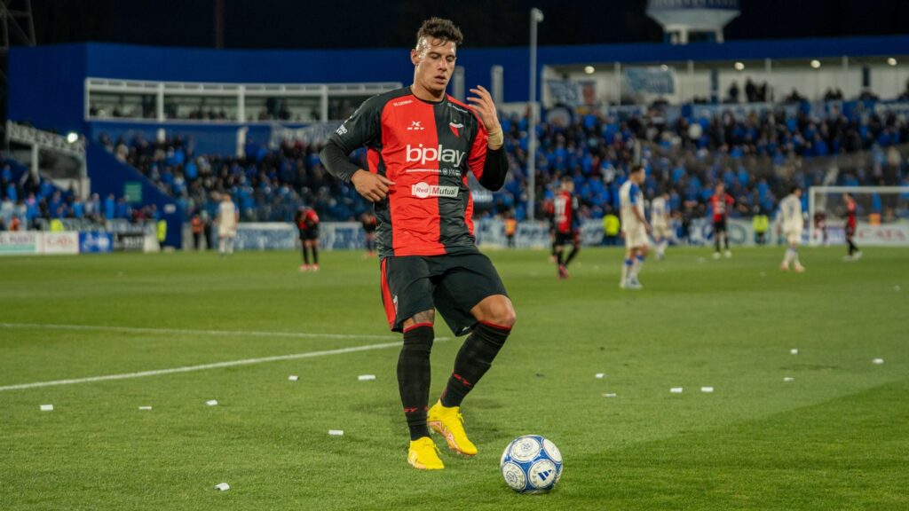 Soccer player controlling the ball during a match on a lush green field.