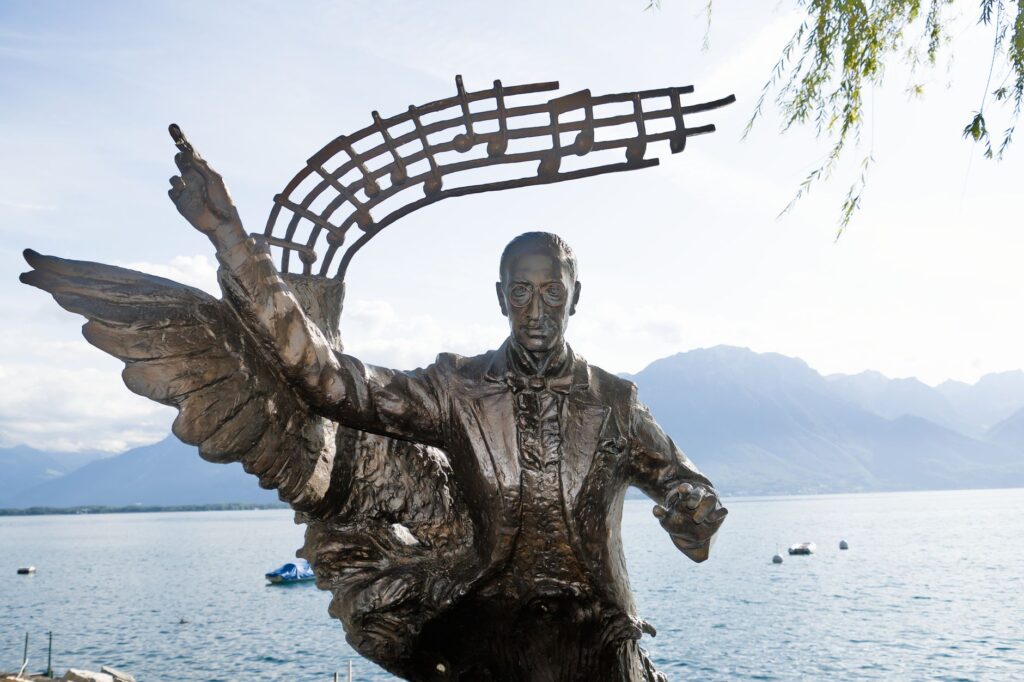 A striking statue of composer Igor Stravinsky with Lake Geneva and mountains in the background.