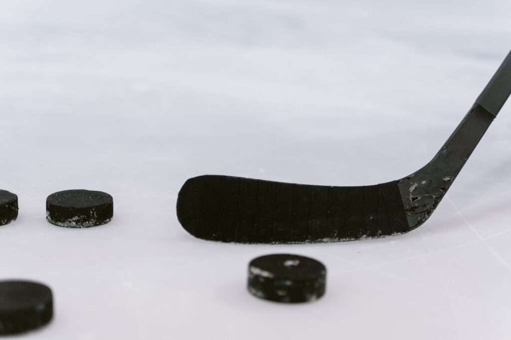 Detailed view of a hockey stick and pucks on ice, perfect for sports visuals.