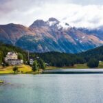 Scenic view of San Maurizio Lake with mountains and forest in Switzerland's Graubünden region.