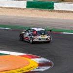 High-speed race car taking a sharp turn at Portimão Circuit, Portugal.