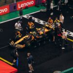 A Formula 1 pit crew preparing a car for the race on a rainy day, teamwork in action.