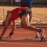 Athlete in red preparing to sprint on an outdoor track field. Focus on starting technique.
