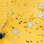 Shiny golden trophy and stars on a vibrant yellow background, symbolizing success and victory.