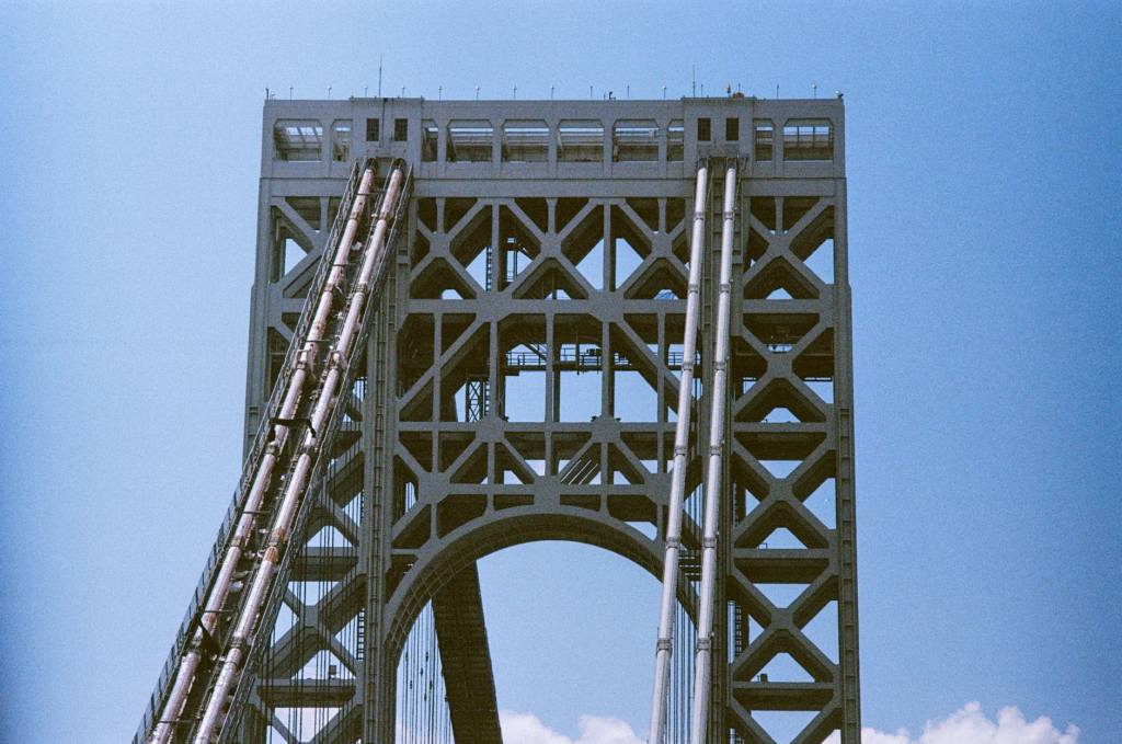 Architectural detail of a bridge tower under blue skies, showcasing geometric design.