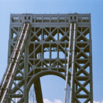 Architectural detail of a bridge tower under blue skies, showcasing geometric design.