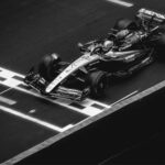 Black and white image of a Formula 1 car crossing the finish line on the track.