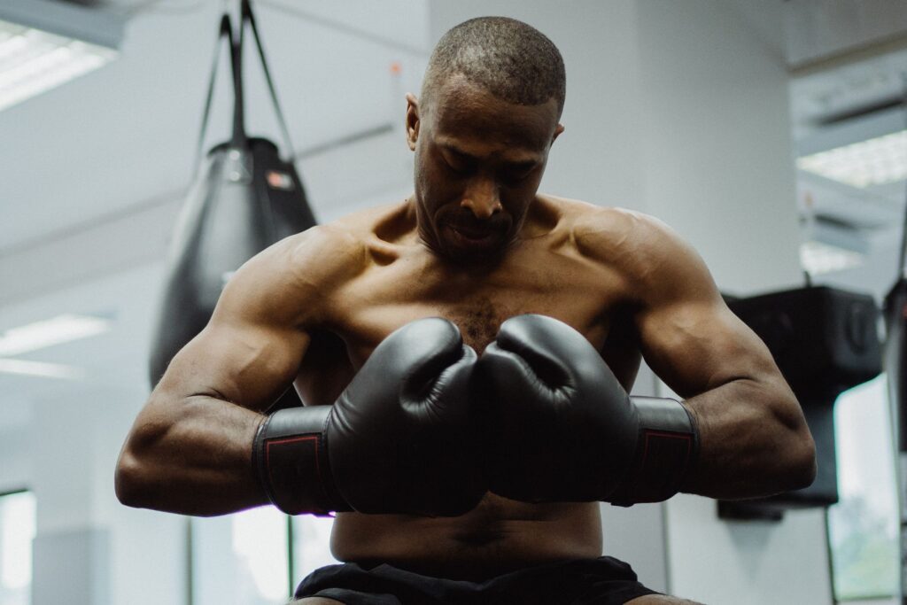 Athlete preparing for an intense training session in the gym, wearing boxing gloves and focusing on fitness.