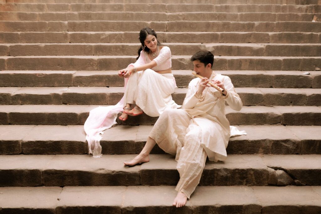 A couple in traditional Indian clothing sitting on stone steps, enjoying a moment.