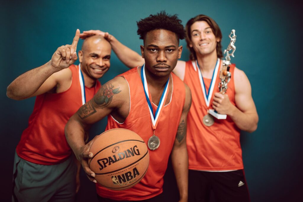 Three basketball players celebrating victory with trophies and medals, showcasing teamwork and accomplishment.