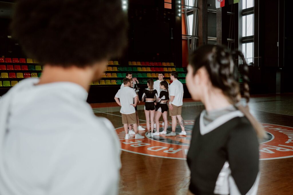 A cheerleading team gathers for practice in a brightly lit gymnasium.