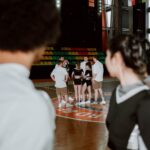 A cheerleading team gathers for practice in a brightly lit gymnasium.