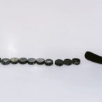 A row of hockey pucks and a stick on an ice rink, perfect for sports content.