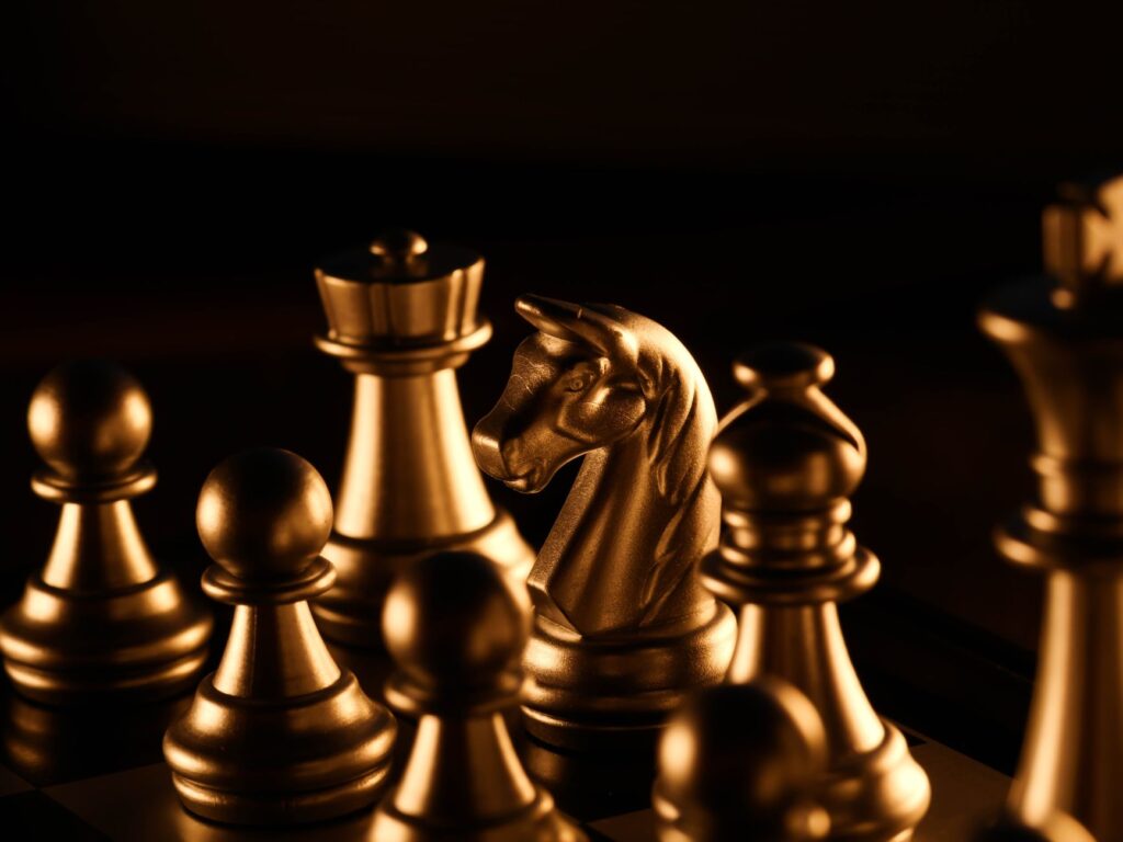 Dramatic close-up of golden chess pieces on a chessboard under warm lighting.
