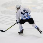 Ice hockey player wearing jersey number 10 skating on an ice rink during a game.