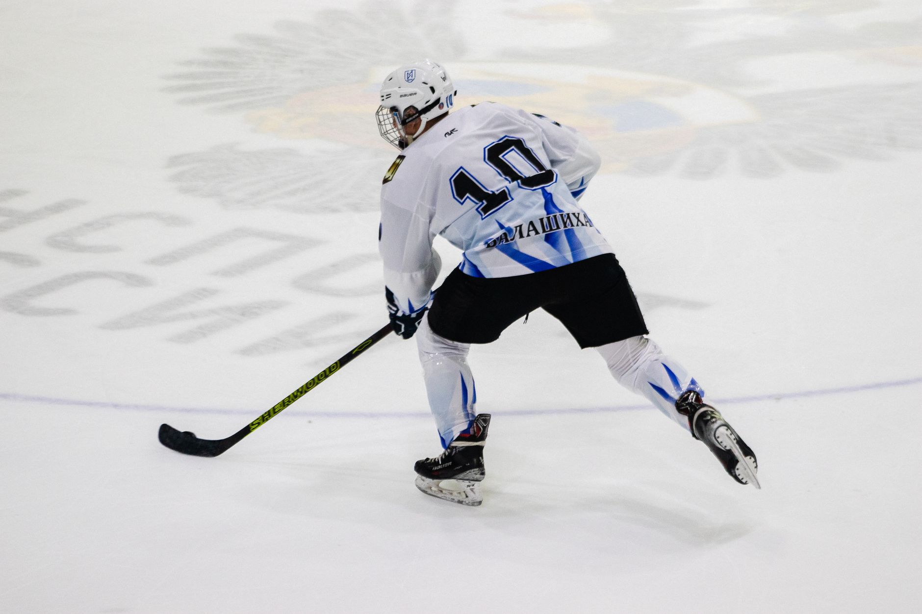 Ice hockey player wearing jersey number 10 skating on an ice rink during a game.