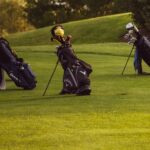 Set of golf bags on a sunlit golf course ready for a game.
