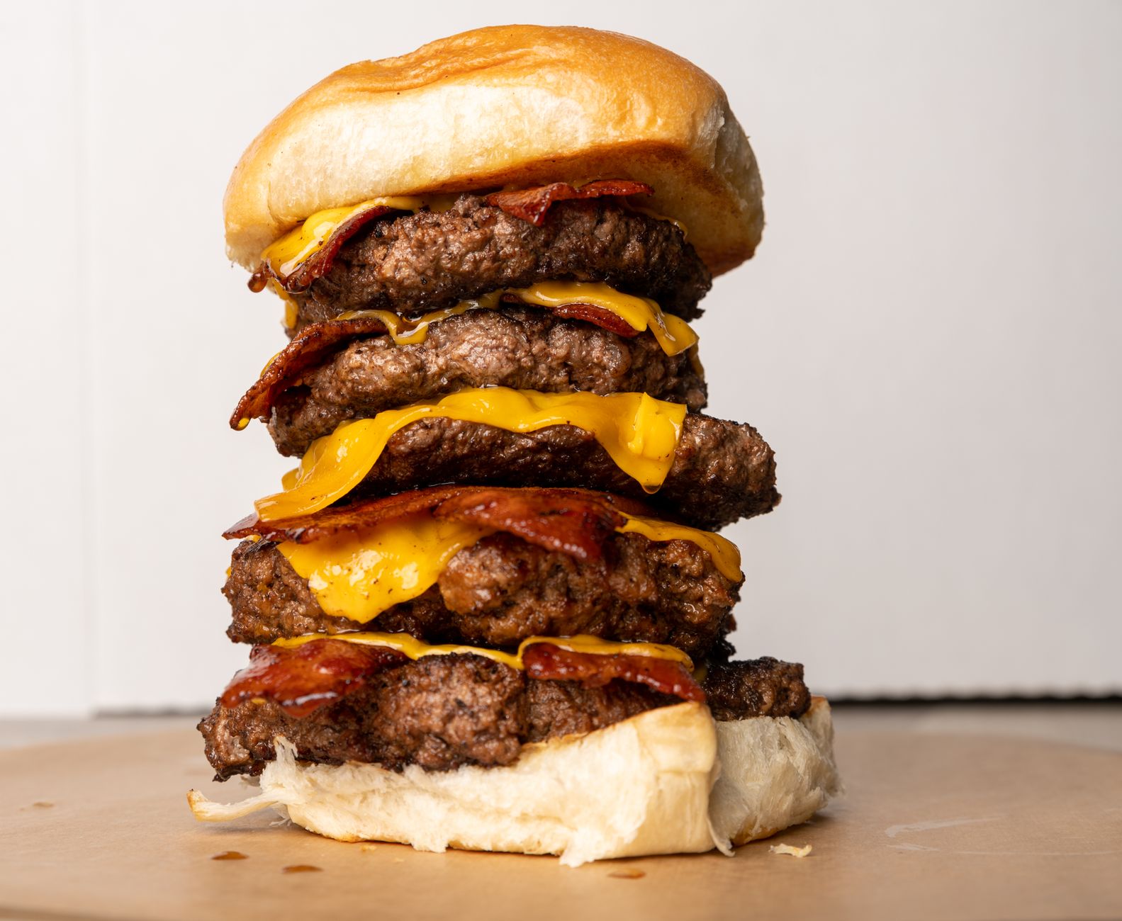 Delicious triple-stacked bacon cheeseburger with melted cheese, perfect for food lovers.