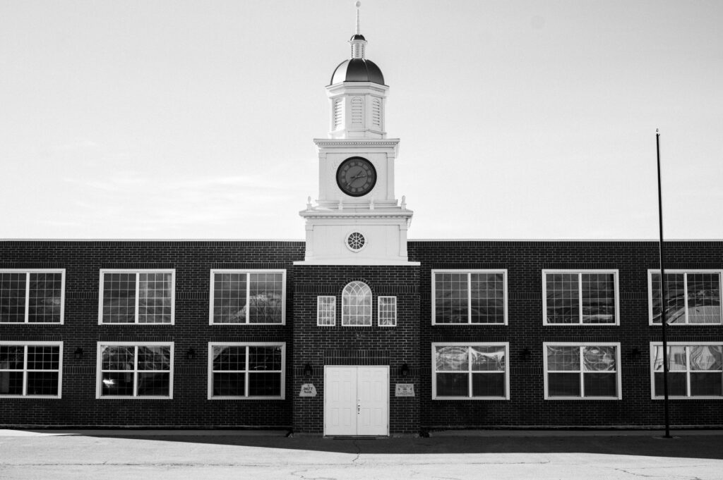 Monochrome image of a clock tower on a classic brick building with clear sky.