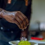Close-up of a chef seasoning an avocado dish, adding a touch of culinary art to gourmet cooking.