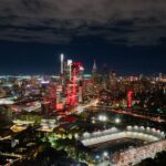 A breathtaking aerial view of Philadelphia's illuminated skyline at night, highlighting the vibrant cityscape and a prominent stadium.