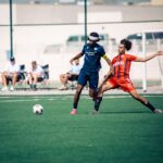 A dynamic moment in an outdoor soccer match with two players in action, competing for the ball.