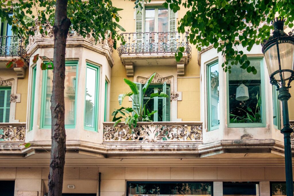 A detailed view of a historic building facade with bay windows and lush greenery in an urban setting.