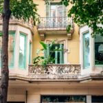 A detailed view of a historic building facade with bay windows and lush greenery in an urban setting.