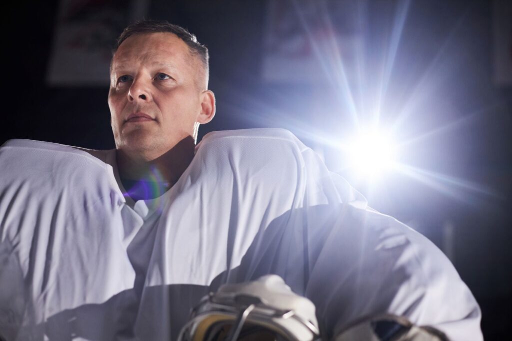 A focused ice hockey player in professional gear under stadium lights, ready for the game.