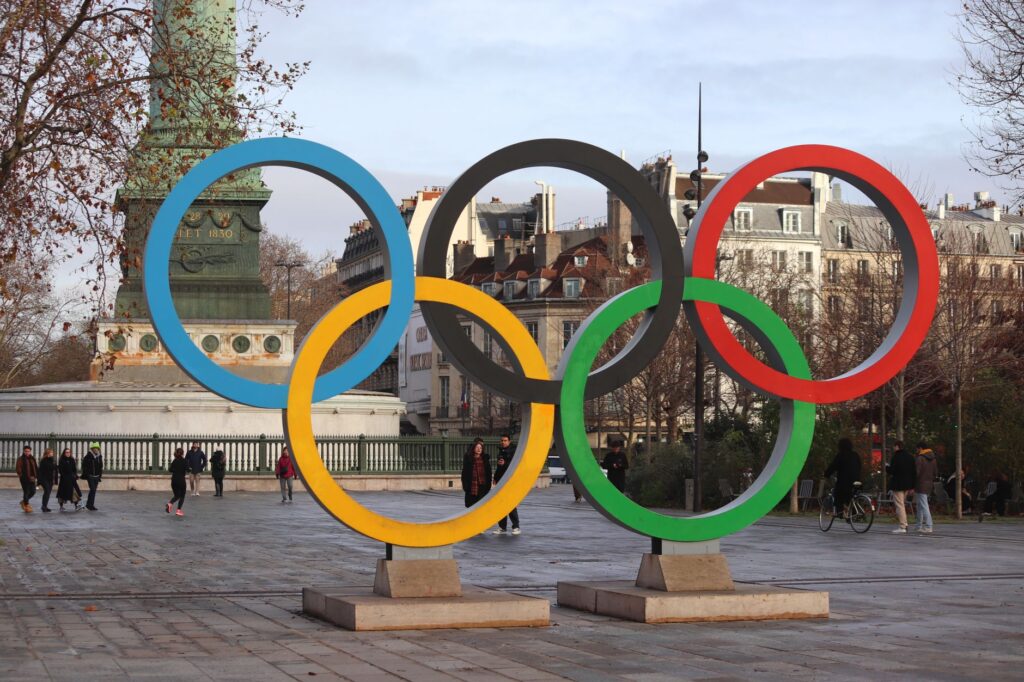 Iconic Olympic rings with city backdrop in Paris, capturing sports spirit.