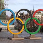 Iconic Olympic rings with city backdrop in Paris, capturing sports spirit.