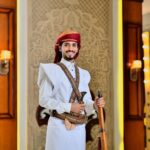 Man in traditional Saudi Arabian attire with ornate decor in Makkah Province setting.