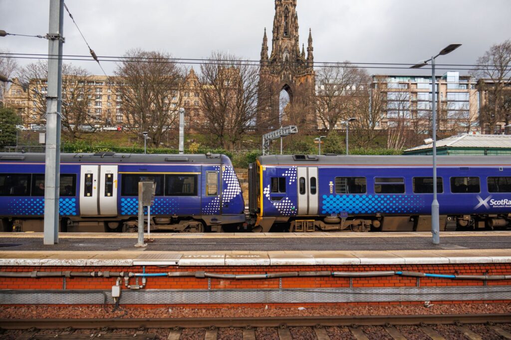 ScotRail train captured by the iconic Scott Monument in Edinburgh, highlighting urban transport.