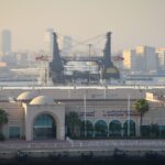 View of Al Maktoum Terminal with cranes and Dubai skyline in the background.