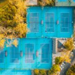 A vibrant aerial view showcasing multiple tennis courts surrounded by autumn trees.
