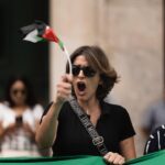 Woman passionately protesting in Rabat, Morocco, waving flag and shouting slogans.
