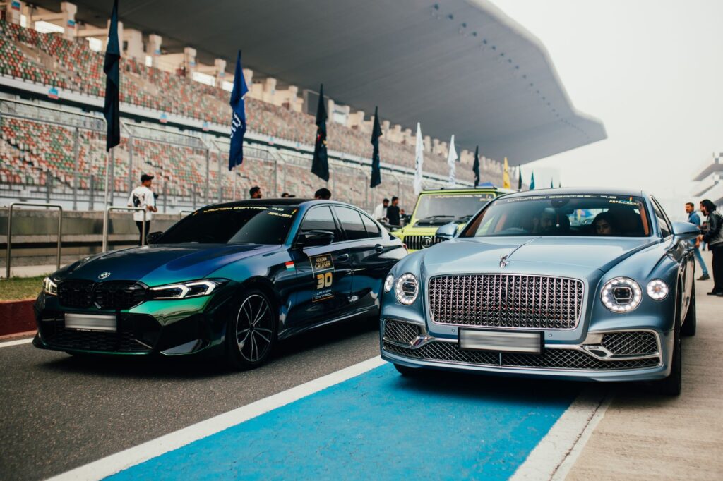 Elegant lineup of luxury cars at a racing event in Greater Noida, India, showcasing Bentley and BMW models.