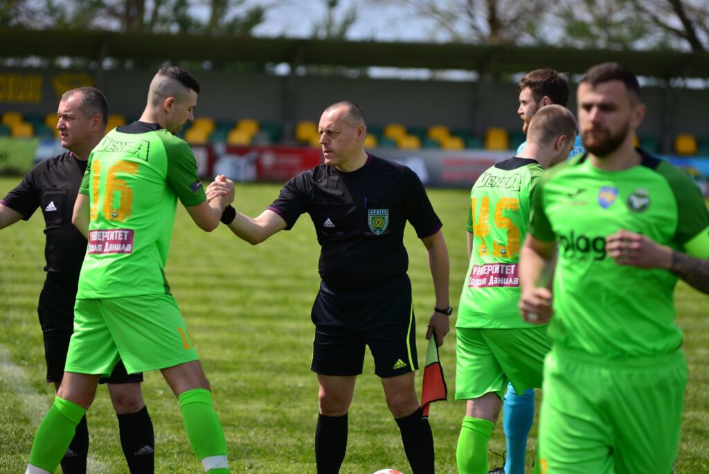 Football players in green jerseys shaking hands with a referee before the match.