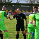Football players in green jerseys shaking hands with a referee before the match.