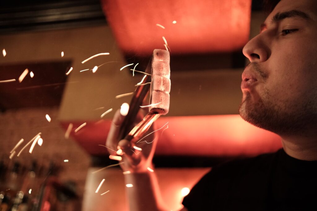 A blacksmith focuses on shaping hot iron, with sparks flying in an atmospheric setting.