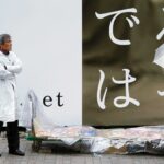 Street vendor and passerby with umbrella under rain in Tokyo, contrasting Japanese urban scene.